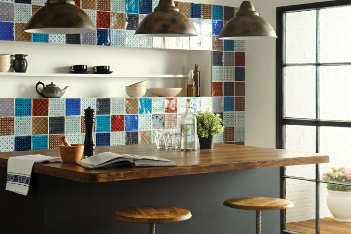 Stylische Küche mit Holztheke, bunten Wandfliesen, Regal mit Geschirr und Barhockern im Industriestil