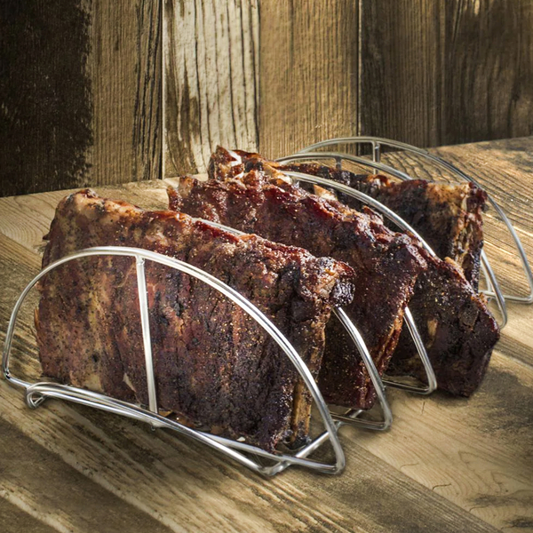 Mehrere marinierte Spareribs stehen in einem Edelstahl-Rippchenhalter auf einem Holztisch, ideal zum Grillen oder Backen