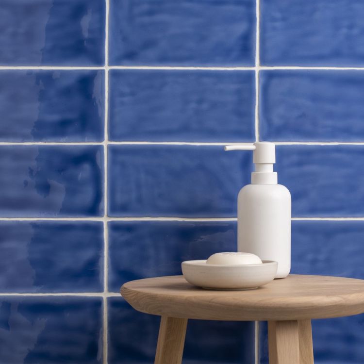 Blaue Wandfliesen, glänzend; Seifenspender auf Hocker