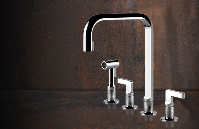 Vierteilige Design-Küchenarmatur in glänzender Chrom-Optik vor rustikal dunklem Hintergrund, bestehend aus Wasserhahn, Handbrause und zwei Bedienhebeln