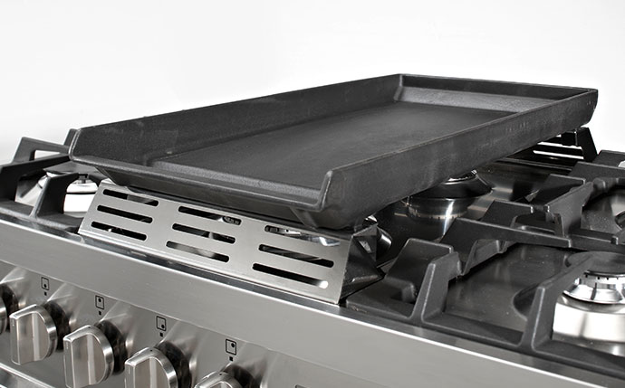 Schwarze Gusseisen Grillplatte auf einem Edelstahl-Gasherd mit Drehknöpfen, geeignet zum Grillen und Braten