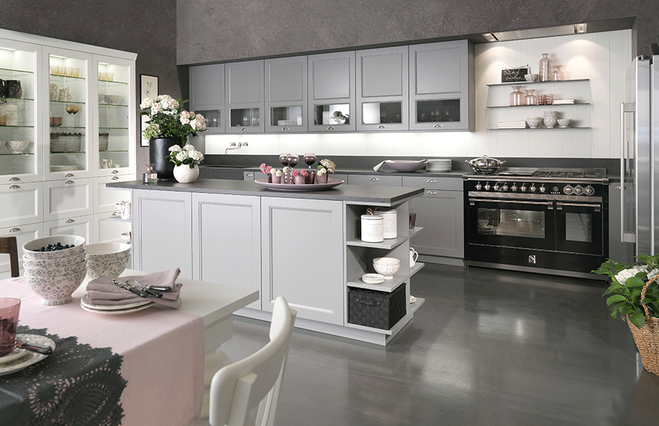Helle, moderne Küche mit grauen Schränken, Kücheninsel, Esstisch mit rosa Tischdecke und stilvoller Dekoration