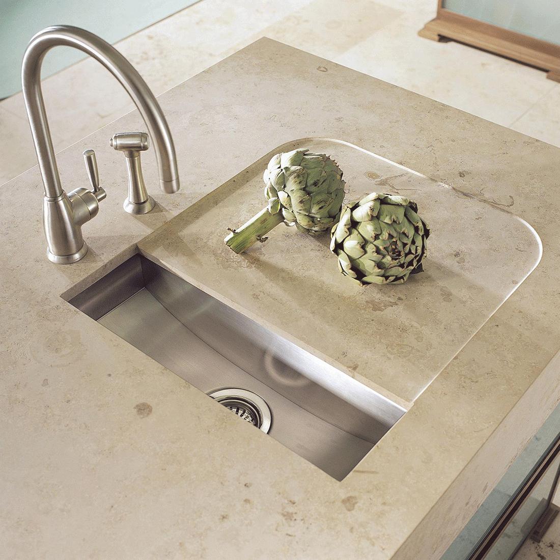 Küchenspüle aus Edelstahl in heller Arbeitsplatte mit zwei Artischocken und moderner Wasserhahn-Armatur