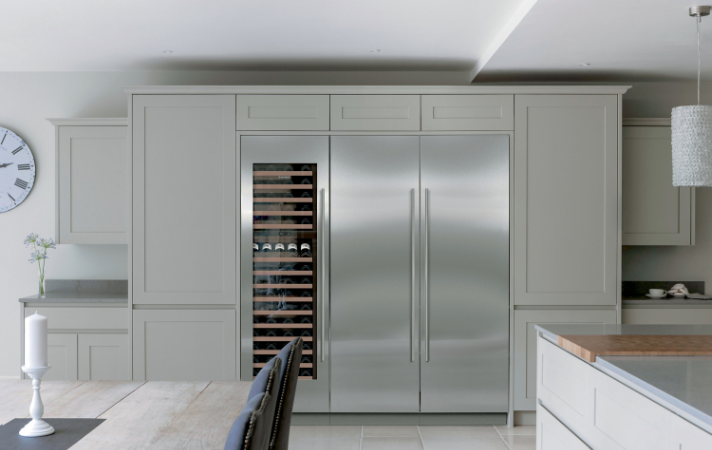 Helle, moderne Einbauküche mit großem Side-by-Side Kühlschrank und integriertem Weinkühler, Esstisch im Vordergrund