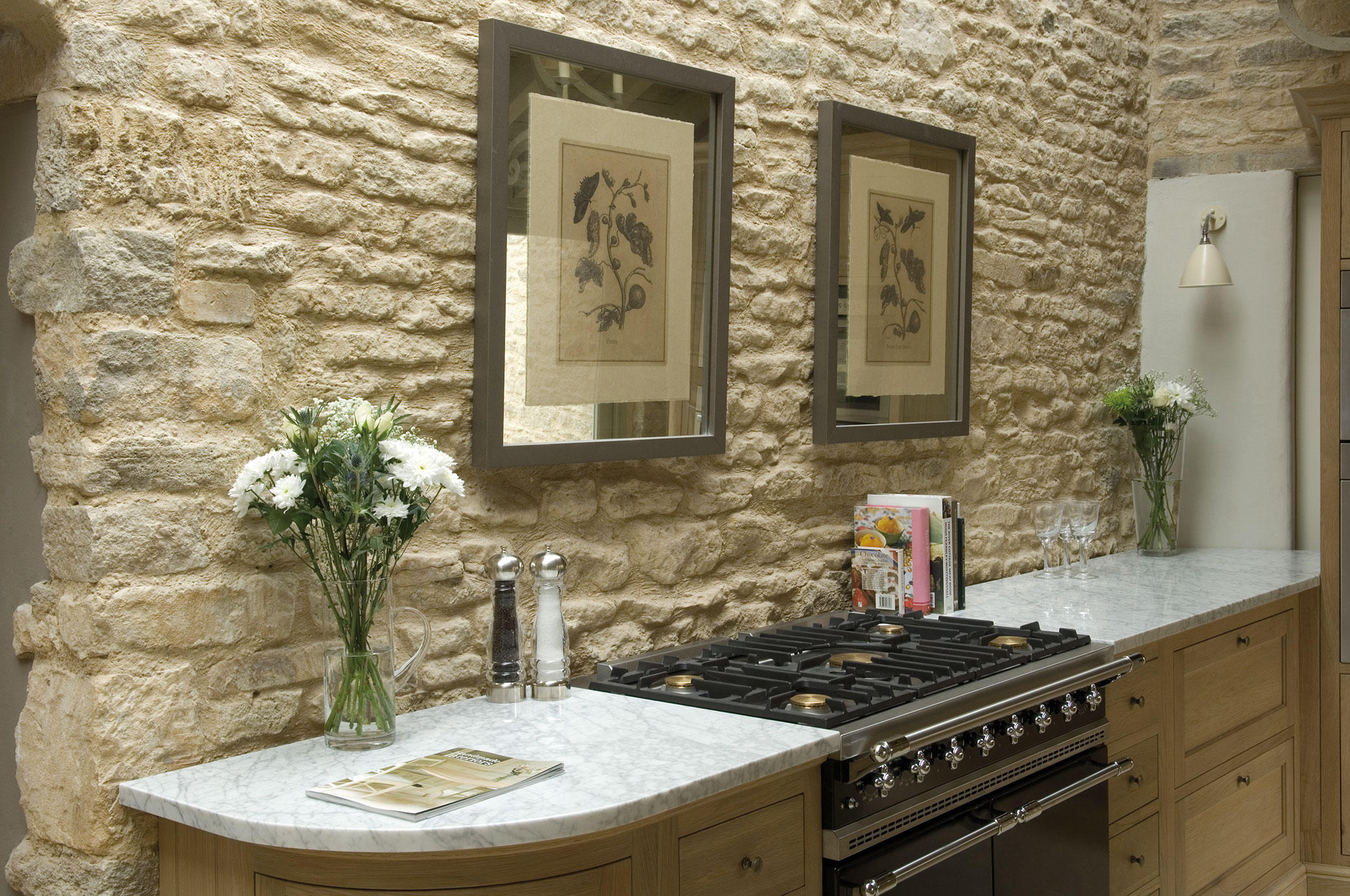 Helle Küche im Landhausstil mit rustikaler Natursteinwand, Gasherd, Marmorarbeitsplatte, Blumenvasen und Wandbildern
