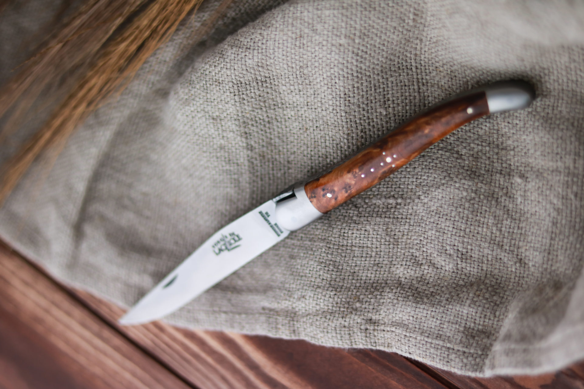 Küchenmesser mit braunem Holzgriff, liegend auf einem strukturierten Leinentuch, ideal für präzises Schneiden