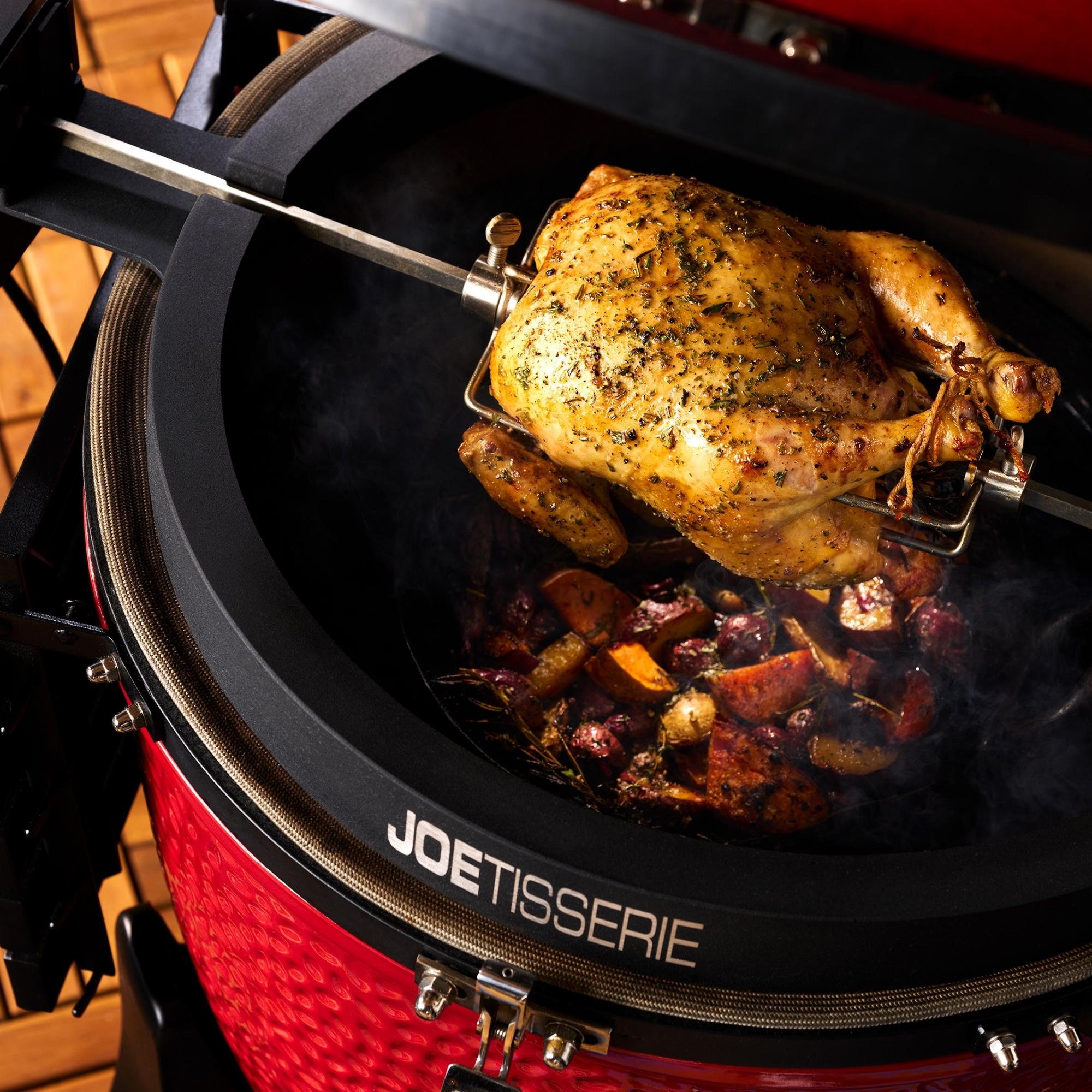 Frisch gegrilltes Hähnchen am Spieß auf einem Kamado Joe Grill mit geröstetem Gemüse darunter