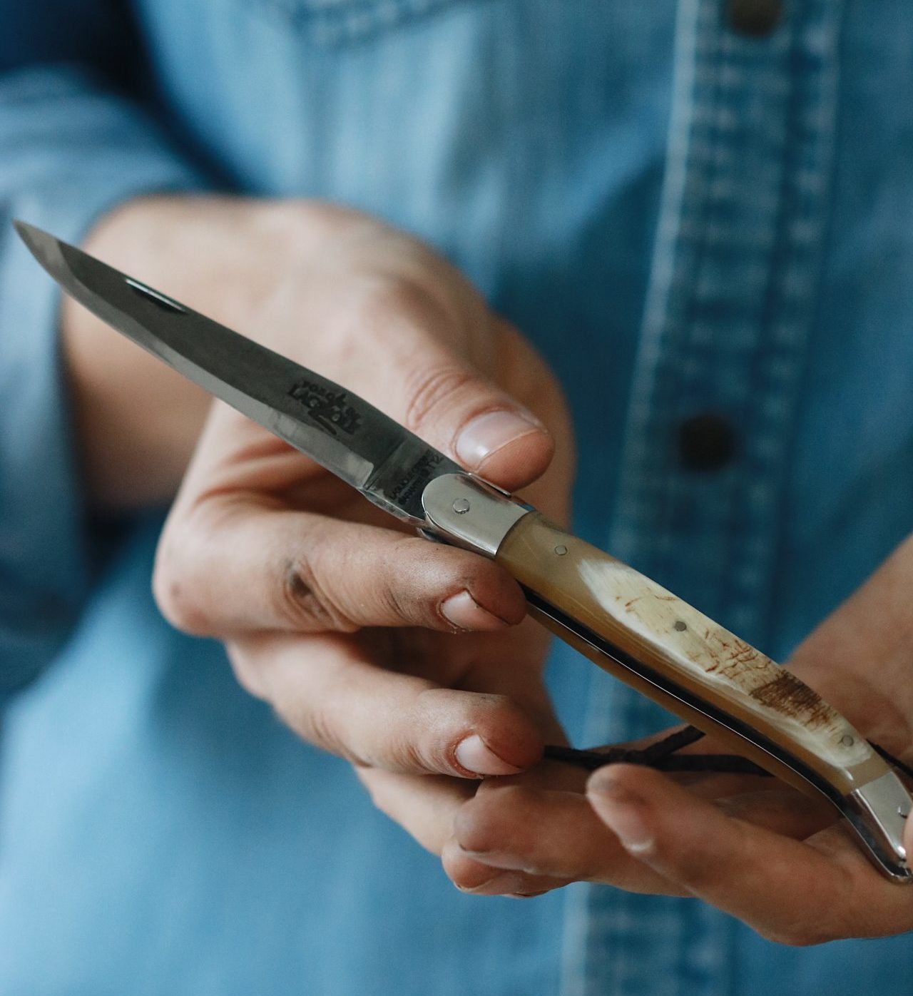 Person hält ein aufgeklapptes Taschenmesser mit Hirschhorngriff in der Hand, Nahaufnahme