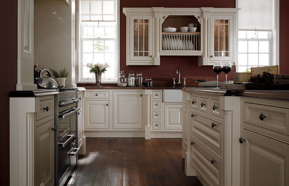 Elegante Landhausküche mit cremefarbenen Schränken, offenem Tellerregal, dunkler Arbeitsplatte und stilvollen Details wie Glastüren und Holzboden