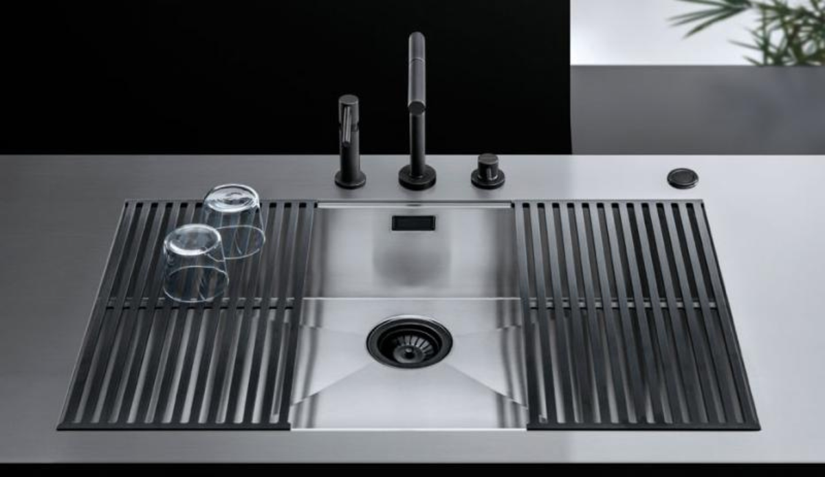 Edelstahlspüle mit schwarzem Wasserhahn, Seifenspender, Drehknopf und zwei auf Abtropfgittern stehenden Gläsern in moderner Küche