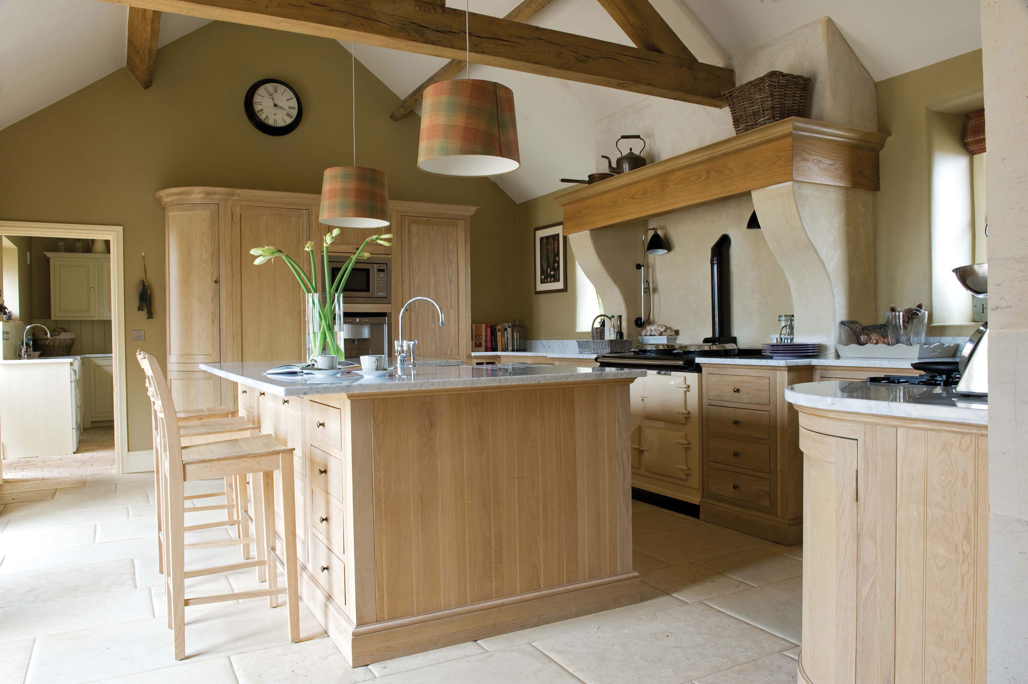 Helle, moderne Wohnküche mit großer Kücheninsel, Holzmöbeln, Marmorarbeitsplatten und zwei Hängelampen, im Landhausstil eingerichtet