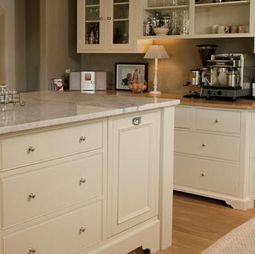 Moderne Küche mit cremefarbenen Fronten, Marmortheke, Kaffeemaschine und Glaselementen in den Oberschränken