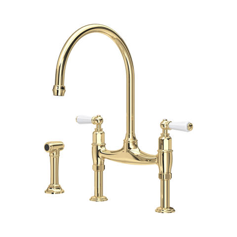 Goldene Küchenarmatur im Brückendesign aus poliertem Messing mit zwei weißen Hebeln, hohem Schwanenhals und separater Seitenbrause – elegante, klassische Spültischarmatur für die Küche