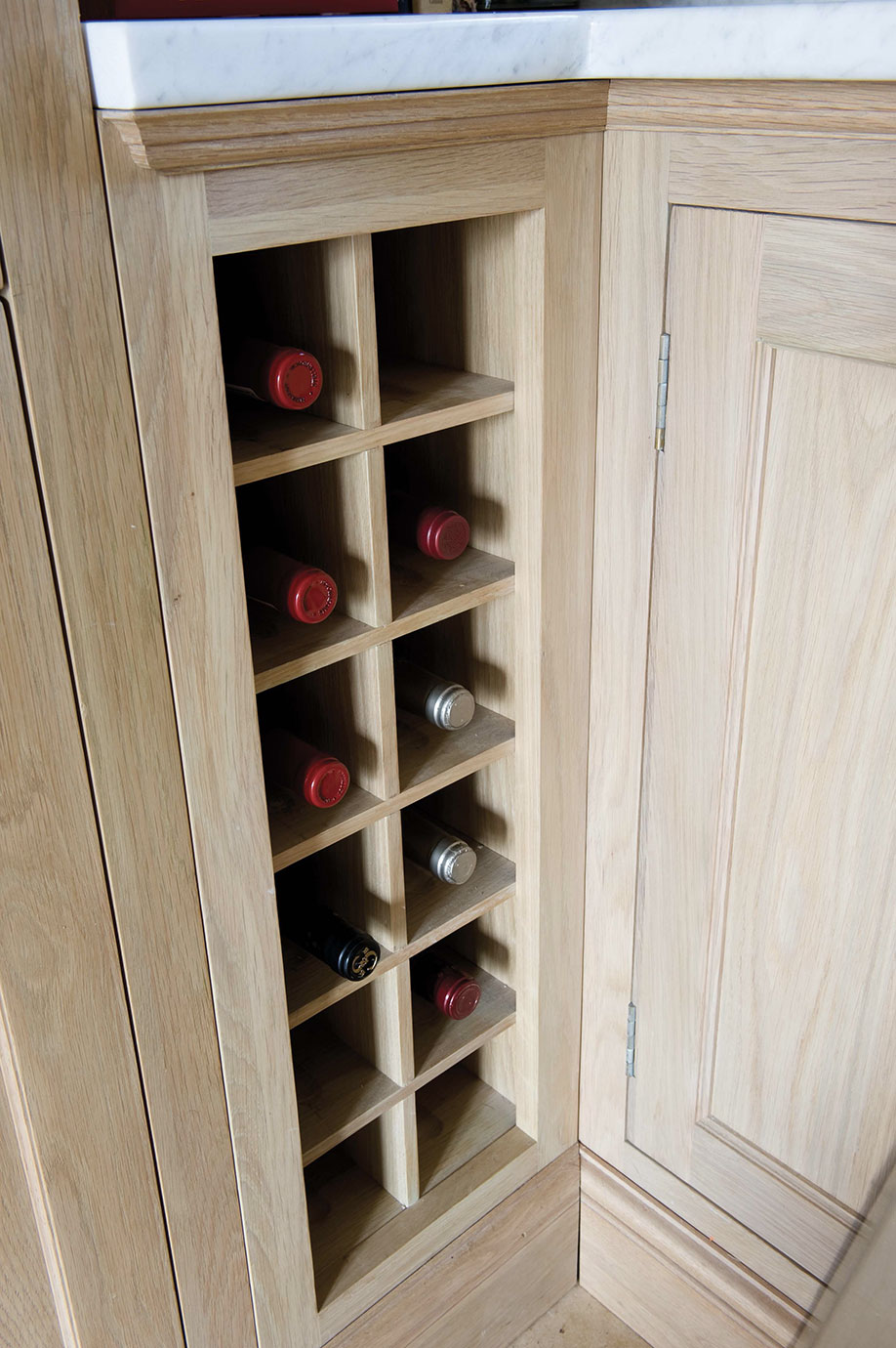 Offenes, in eine Holzküche integriertes Weinregal mit mehreren Fächern, teilweise bestückt mit Weinflaschen