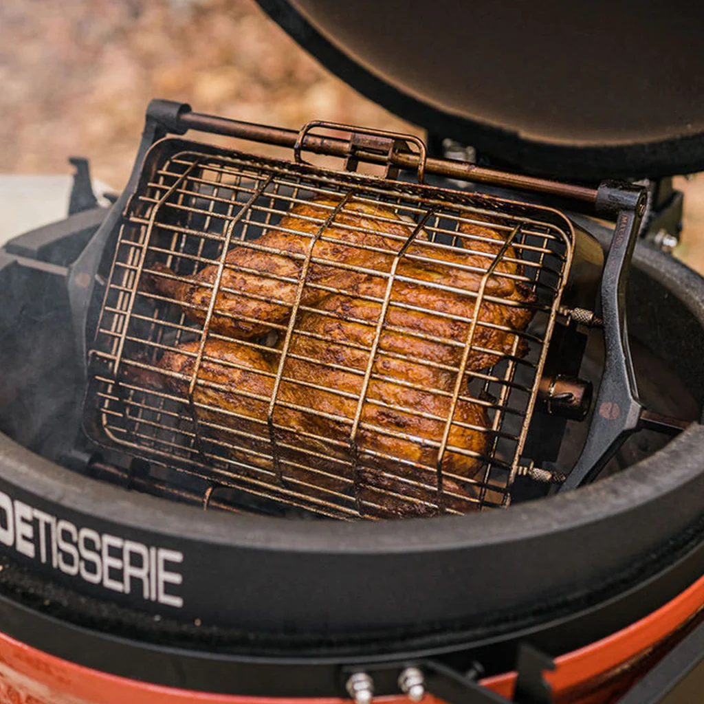 Rippchen werden in einem Rotisserie-Korb auf einem Keramikgrill knusprig braun gegrillt