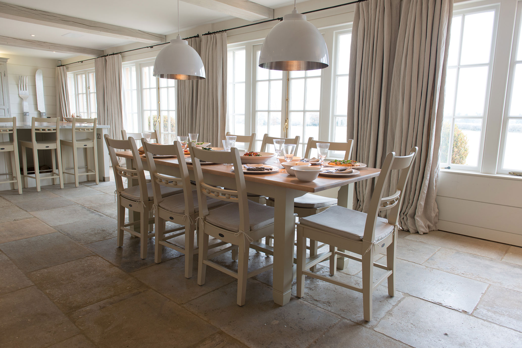 Heller Essbereich mit langem Holztisch, acht gepolsterten Stühlen und modernem Ambiente, gedeckt für ein gemeinsames Essen