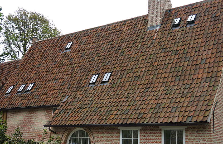 Dach eines Hauses mit roten Ziegeln und mehreren modernen, schwarzen Dachfenstern