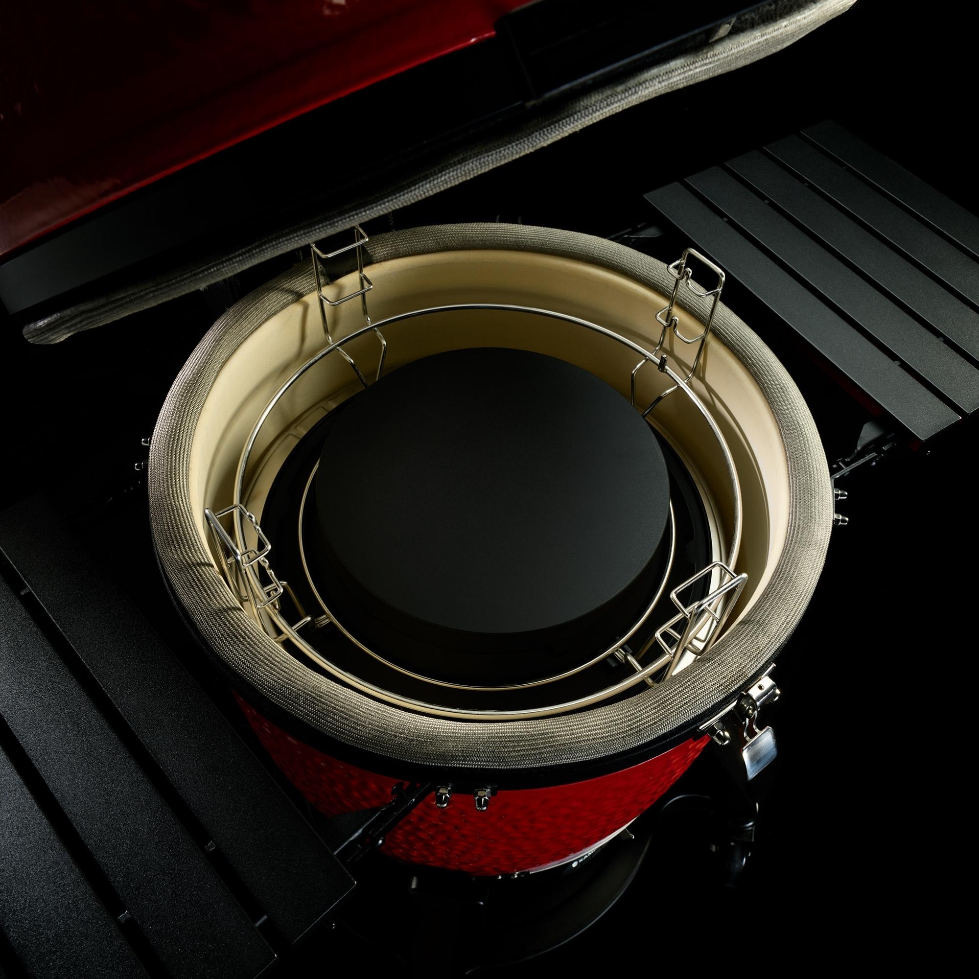 Detailaufnahme eines Kamado-Keramikgrills mit geöffnetem Deckel und eingesetztem Deflektorstein sowie Grillrost, seitliche Ablageflächen sichtbar