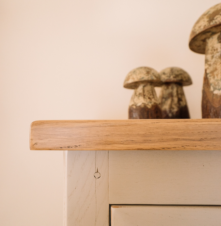 Ein heller Holzschrank mit natürlicher Maserung, darauf stehen drei dekorative Pilzfiguren aus Keramik.