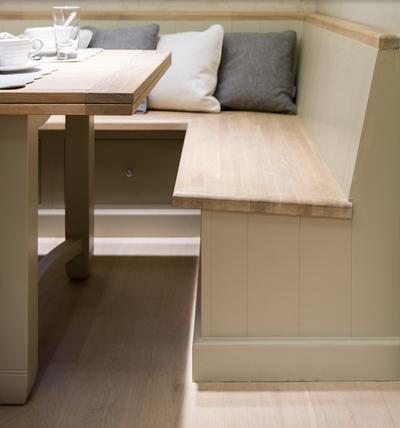 Eckbank aus hellem Holz mit Esstisch und mehreren Kissen, gemütliche Sitzgelegenheit in einer modernen Wohnung