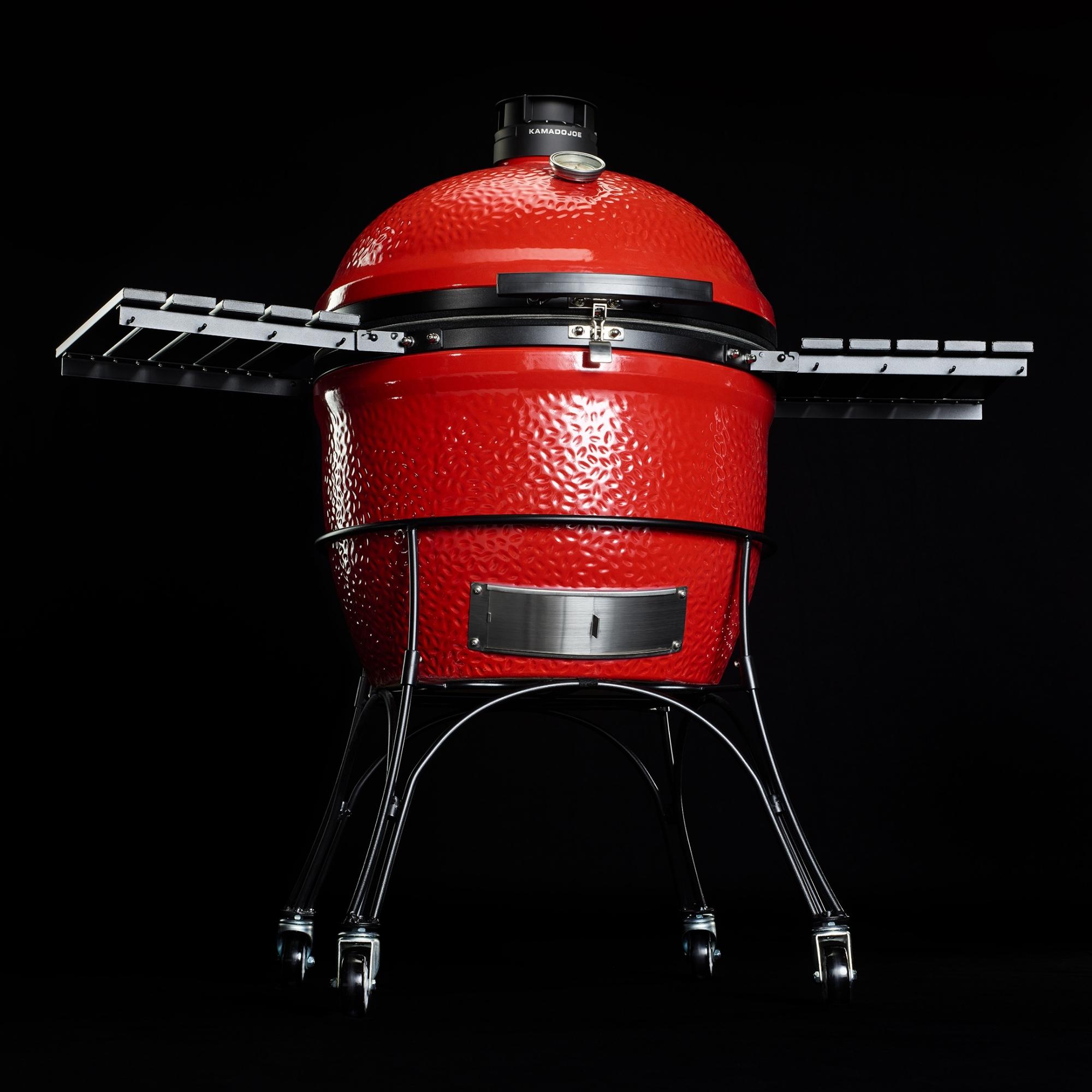 Roter Kamado Joe Classic II Keramikgrill mit Seitentischen, Deckelthermometer und fahrbarem Untergestell auf schwarzem Hintergrund