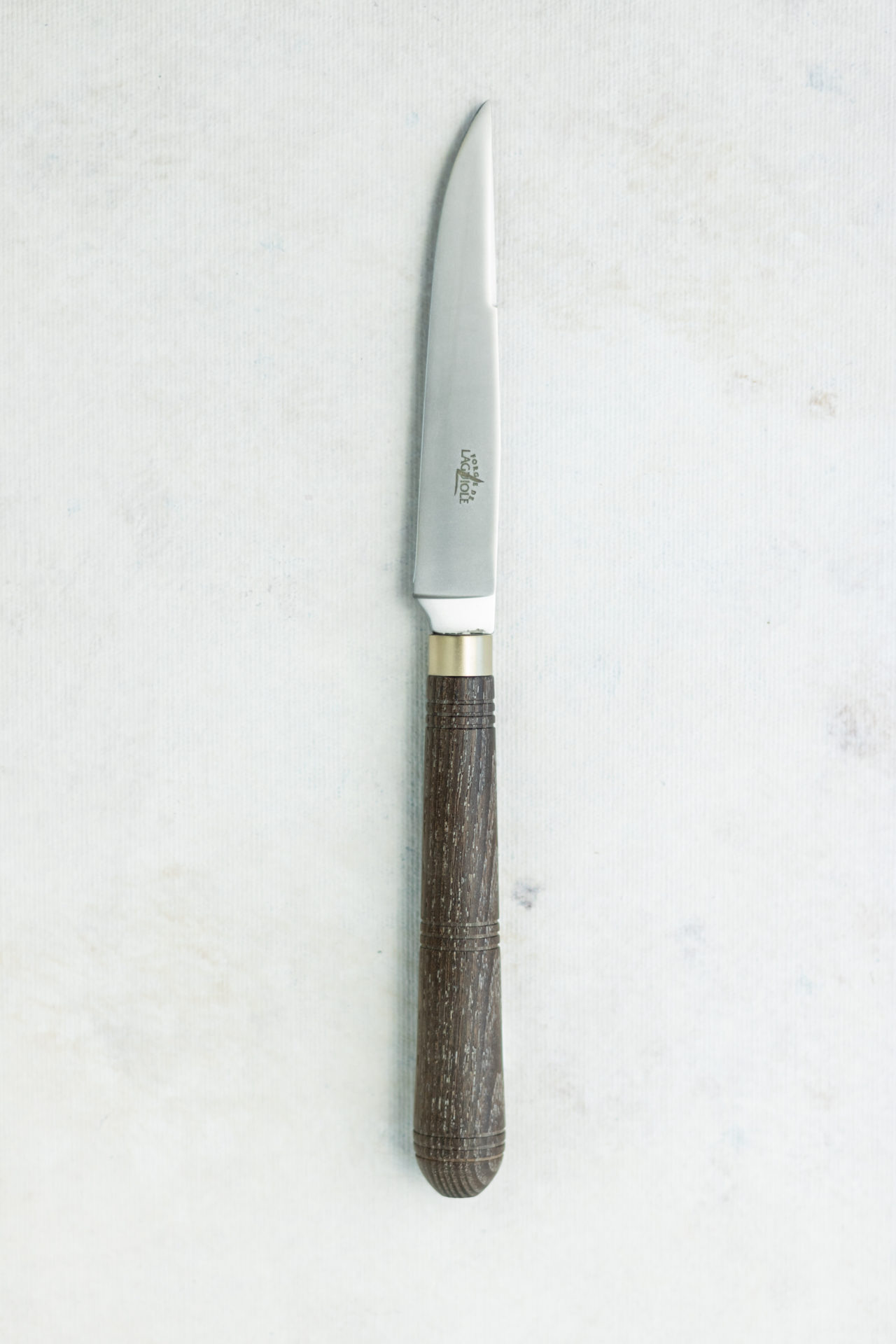 Küchenmesser mit rostfreier Klinge und dunklem Holzgriff auf heller Unterlage