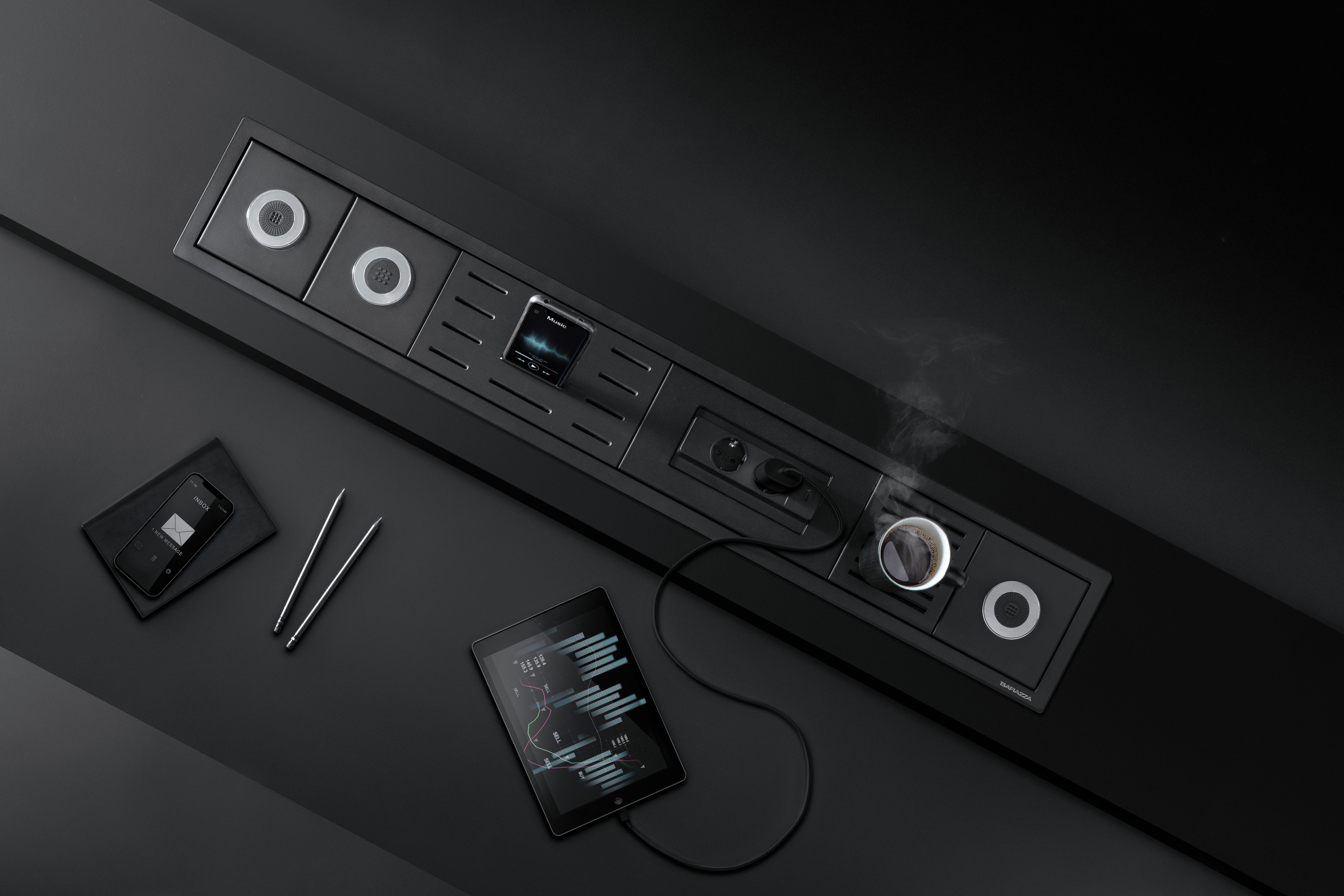Schwarzes Einbaupanel mit Steckdosen, USB-Anschlüssen, Smartphone und Tablet auf einem stilvollen, modernen Schreibtisch
