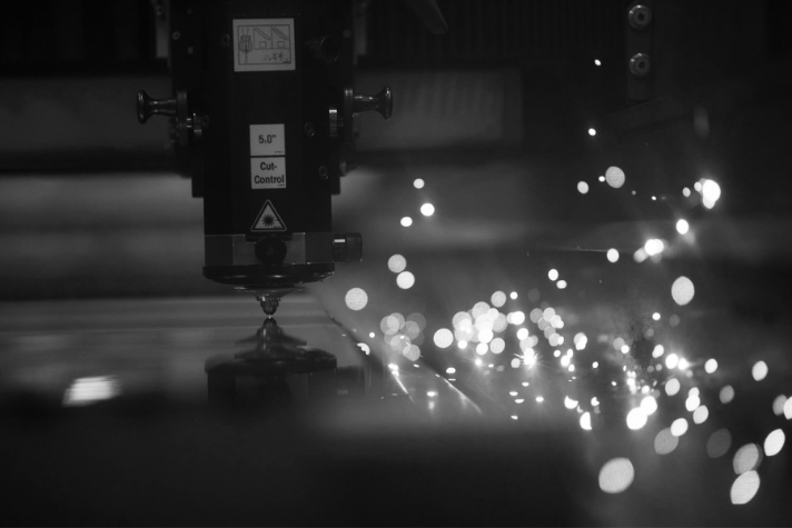 Eine Laserschneidmaschine schneidet Metall, während Funken entstehen, präziser Fertigungsprozess in Schwarzweiß