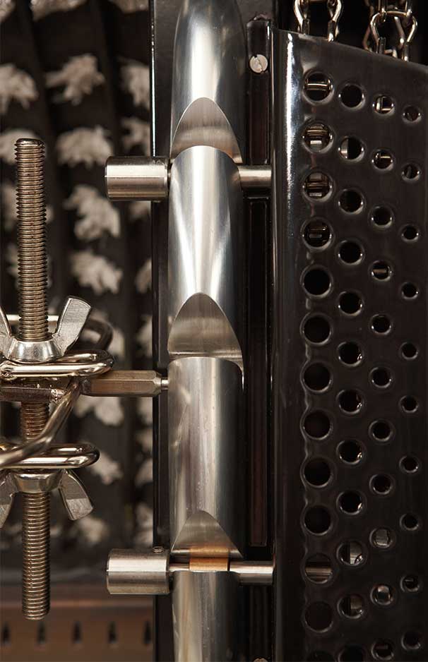 Nahaufnahme eines Edelstahl-Spannmechanismus in Präzisionsbauweise, mit Metallstäben, Scheiben und einer perforierten Abdeckung