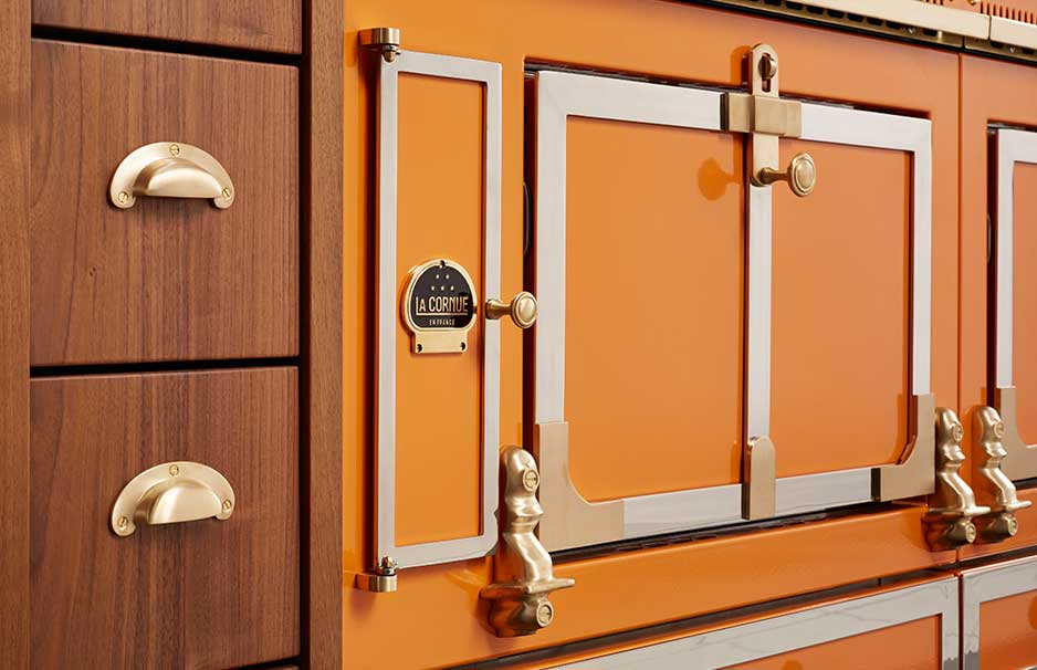 Hochwertiger, orangefarbener La Cornue Herd mit goldfarbenen Griffen und einem Teil von Holzschubladen im klassischen Design