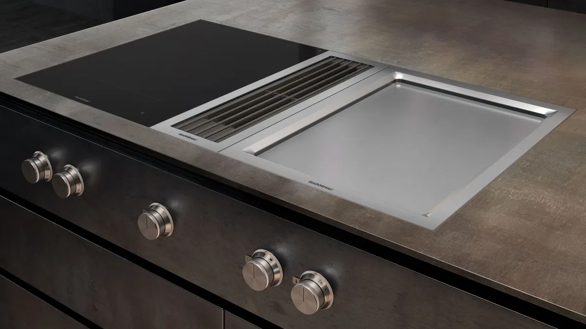 Nahaufnahme eines modernen Kochfelds mit eingelassener Grillplatte aus Edelstahl und integriertem Dunstabzug in einer Küchenarbeitsplatte