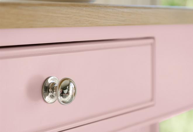 Rosa Schublade mit silbernem Knauf und heller Holzarbeitsplatte im modernen Design