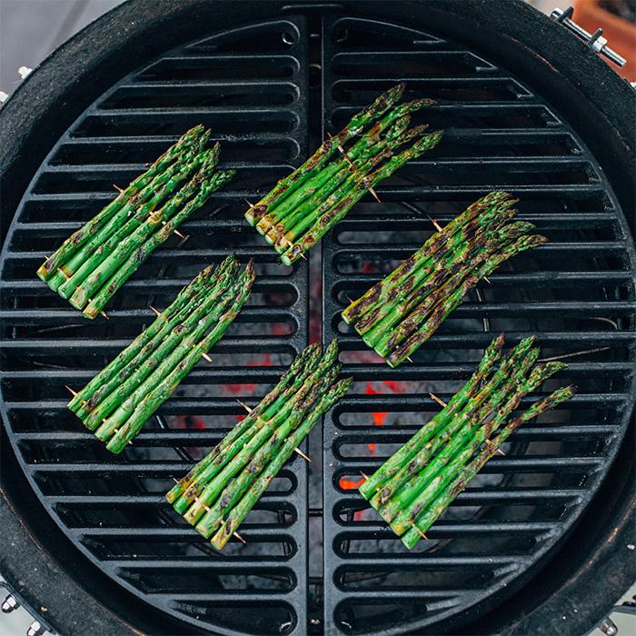 Mehrere Bündel grüner Spargel werden auf einem Grillrost über glühenden Kohlen gegrillt – appetitliche vegetarische Grillbeilage