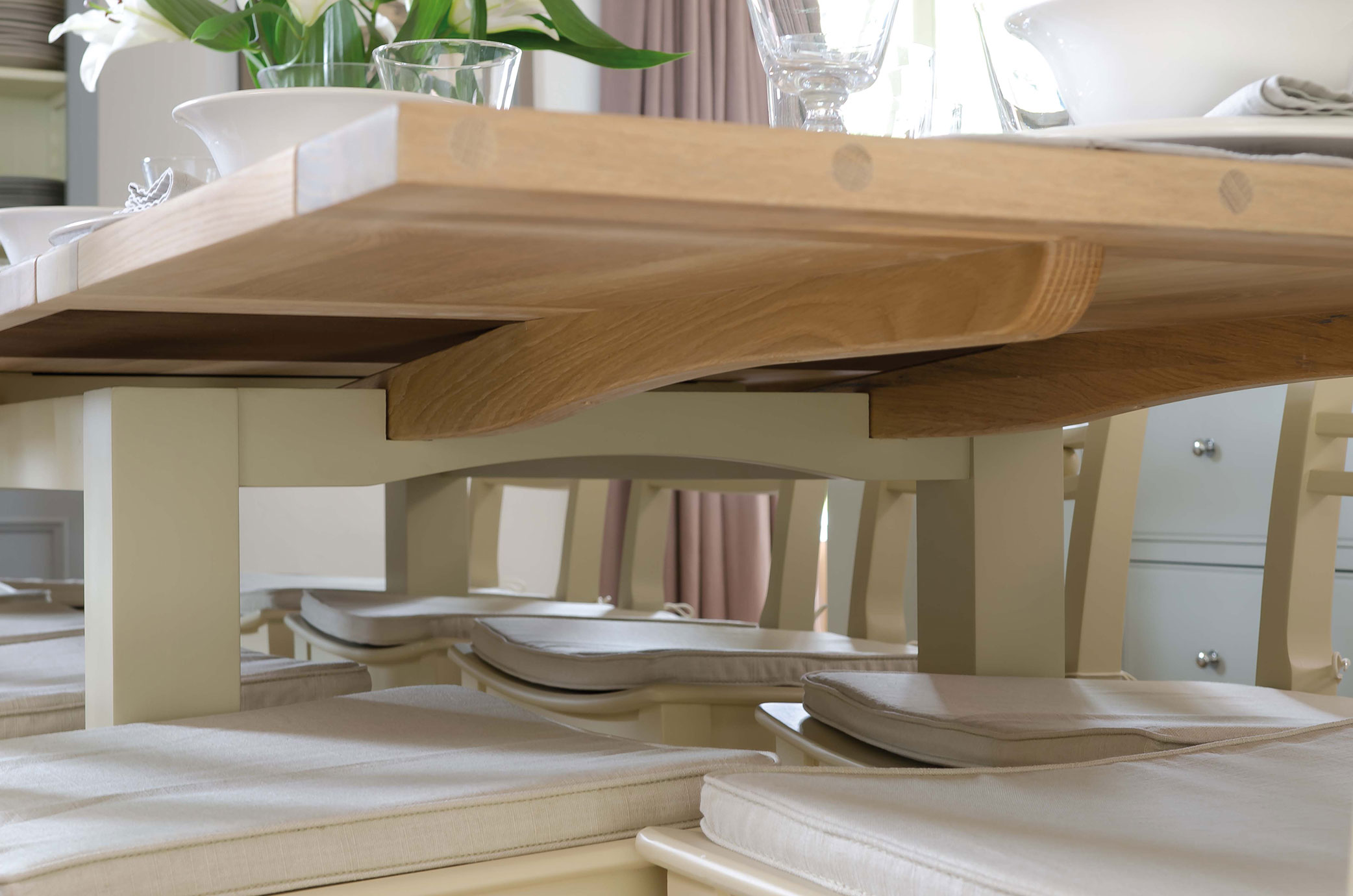 Nahaufnahme eines hellen Holztischs mit beigen Stühlen und Polstern in einem modern eingerichteten Esszimmer