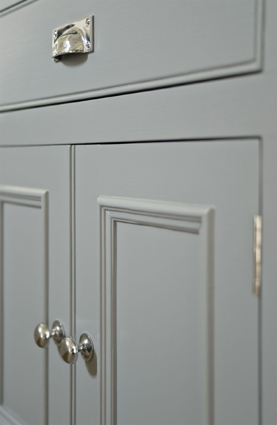 Grauer Schrank mit silbernen Knöpfen und einer Schublade, moderner Look und schlichte Linienführung