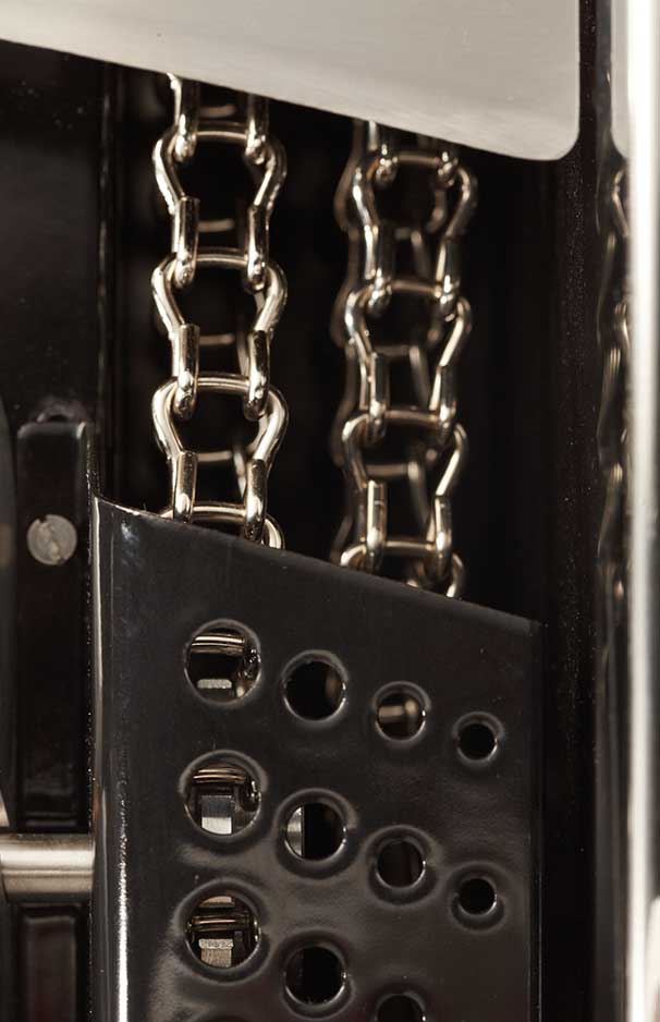 Nahaufnahme von zwei silberfarbenen Metallketten hinter einer schwarzen Metallabdeckung mit runden Löchern