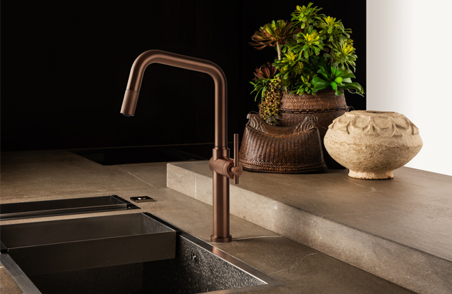 Küchenarmatur in Bronze an einer Design-Spüle mit dekorativen Pflanzen im Hintergrund und edler Keramikvase