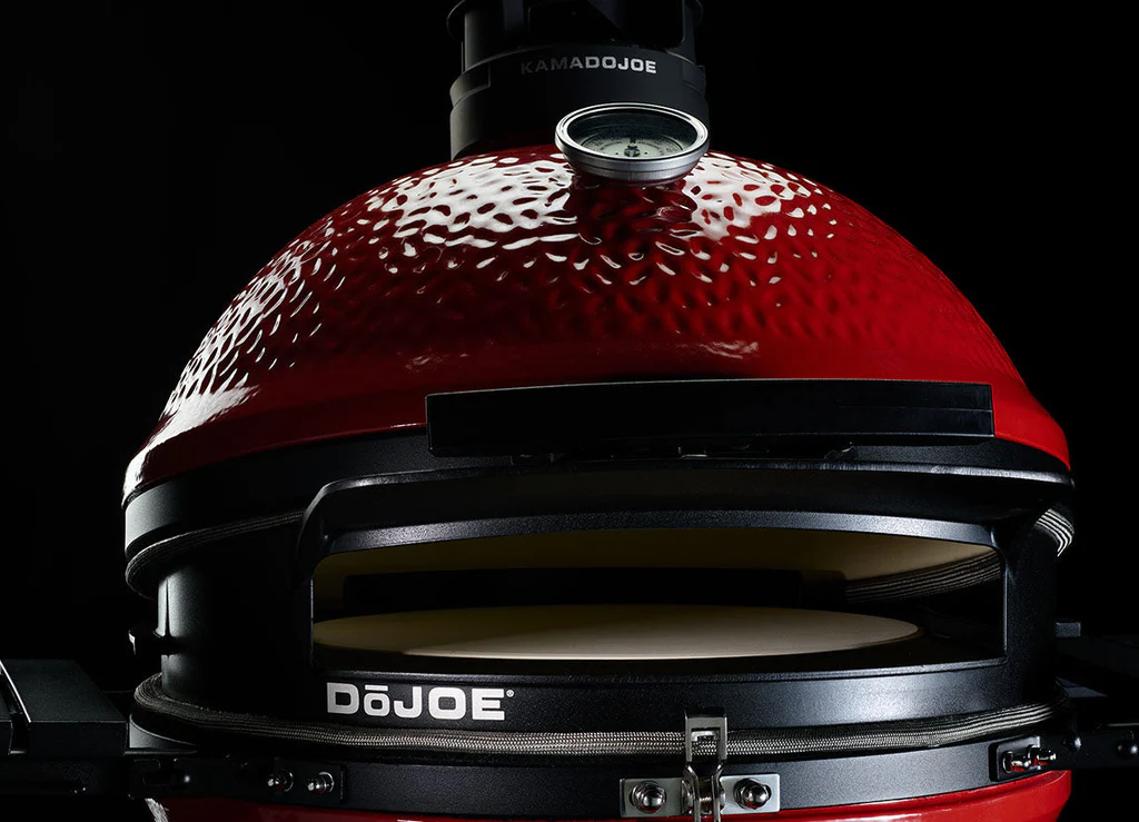 Detailaufnahme eines roten Kamado Joe DoJoe Keramikgrills mit integriertem Thermometer und Pizzastein