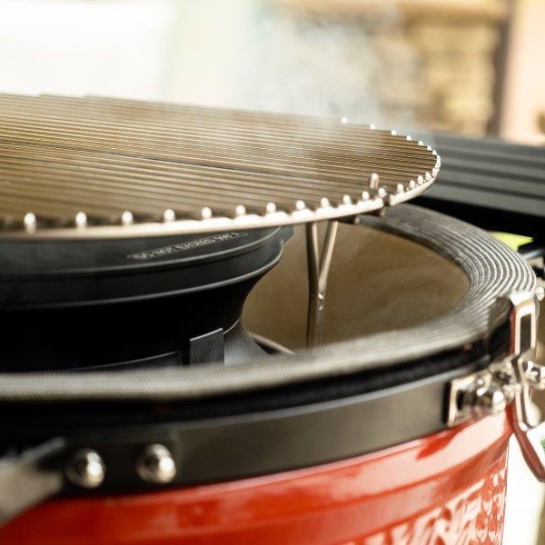 Nahaufnahme eines geöffneten roten Keramikgrills mit Edelstahl-Grillrost, bereit für den Einsatz beim Grillen