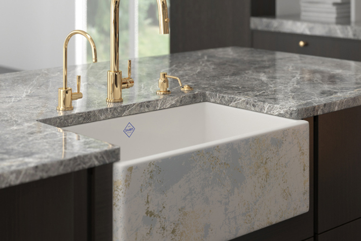 Hochwertige weiße Keramikspüle mit einzigartigem Muster, goldfarbenen Wasserhähnen und eleganter Arbeitsplatte aus grauem Marmor in einer modernen Küche