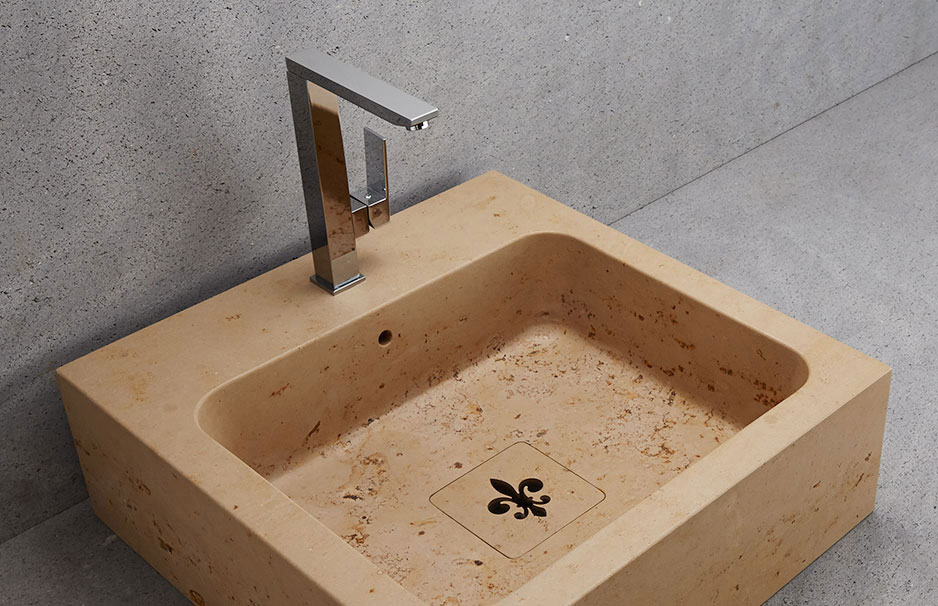 Waschbecken aus beigem Naturstein mit eckiger, moderner Chromarmatur und dekorativem Abflussdesign im Badezimmer