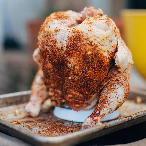 Rohes, gewürztes Bierdosenhähnchen steht aufrecht auf einem Backblech, bereit zum Grillen oder Backen