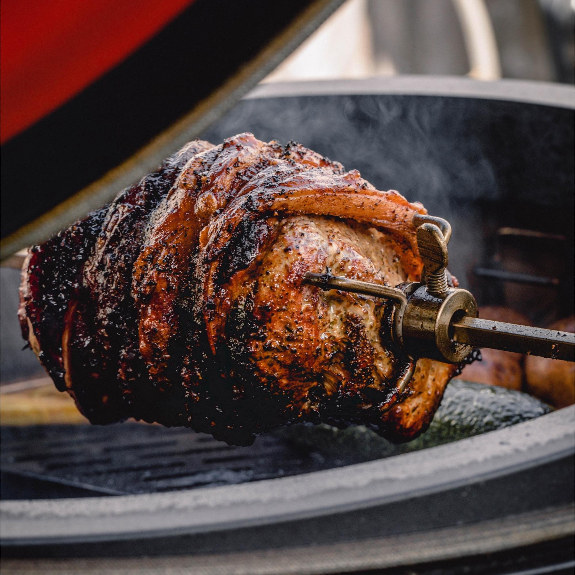Knuspriges Spanferkel am Drehspieß im Grill, goldbraun gebraten und frisch vom Feuer