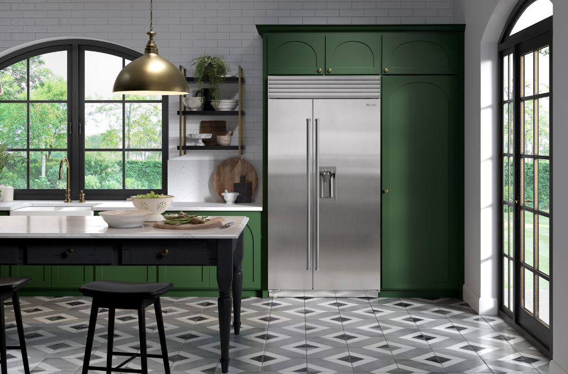 Stilvolle Küche mit grünen Schränken, großem Edelstahl-Kühlschrank, Kücheninsel und großen Fenstern mit Blick ins Grüne