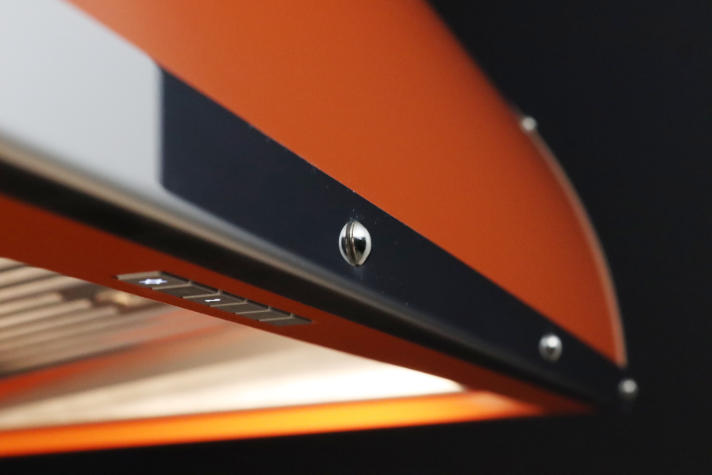 Detailaufnahme einer modernen orangenen Dunstabzugshaube mit LED-Beleuchtung und Bedienelementen