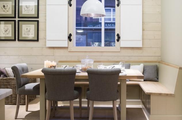 Esszimmer mit Holzbank, grauen Stühlen, Holztisch, Deko-Kerzen und Fenster mit weißen Läden im Landhausstil
