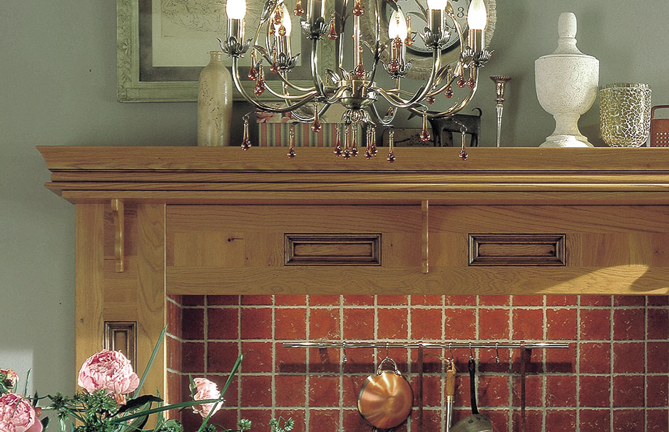 Detailaufnahme einer traditionellen Küche mit Holzelementen, rotem Fliesenspiegel, Kronleuchter sowie dekorativen Accessoires auf dem Regal.
