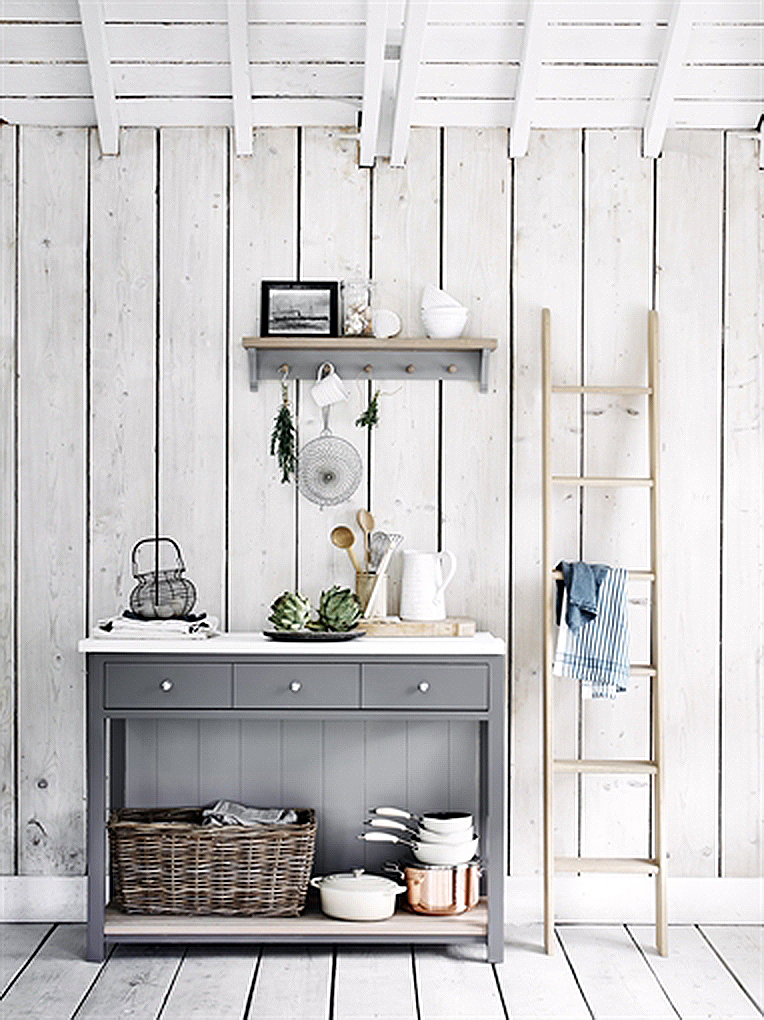 Graues Sideboard mit Küchengeschirr und Korb, dekorative Holzleiter, rustikale Wandverkleidung im skandinavischen Stil