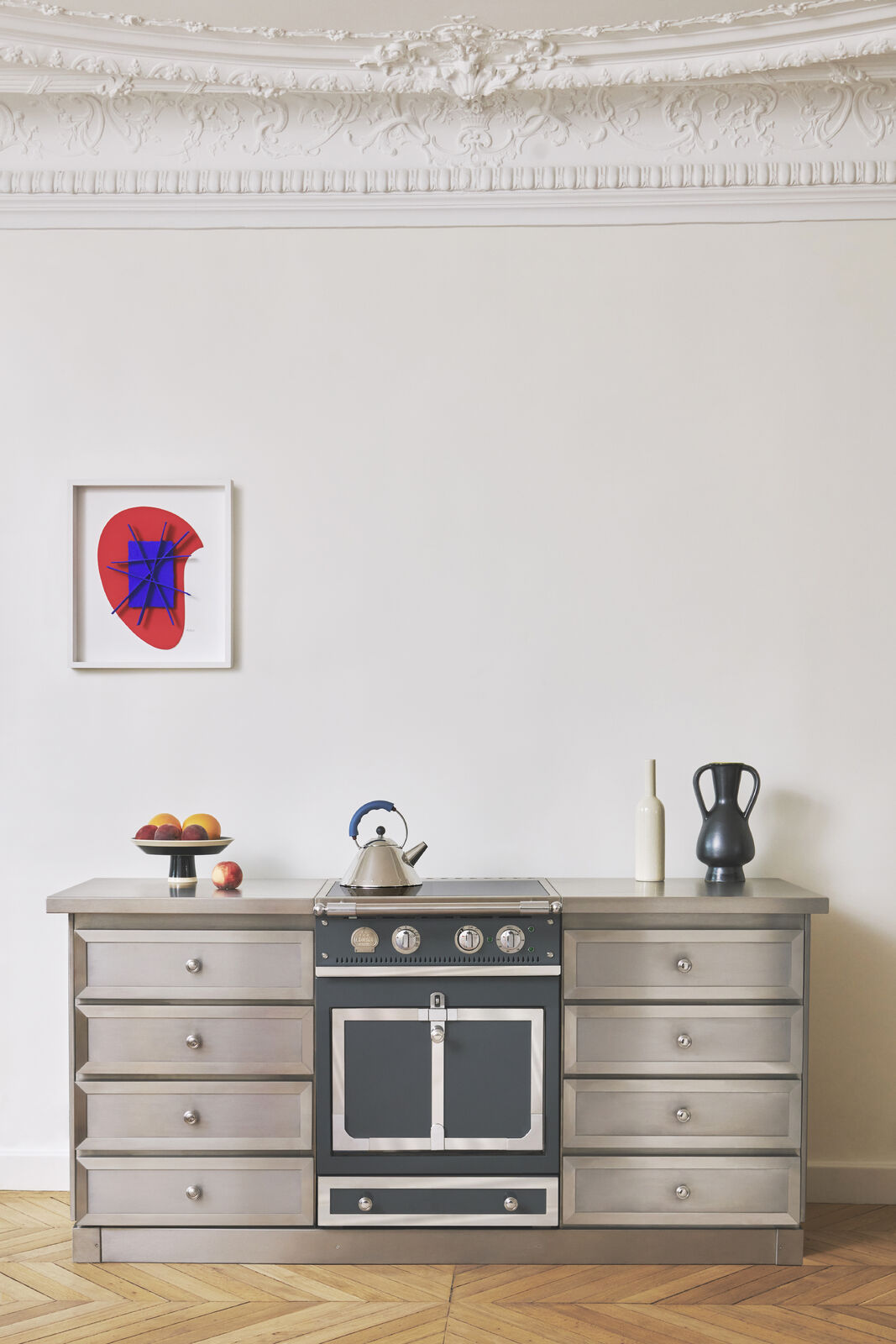 Stilvolle Küche mit edlem Edelstahlherd, Obstschale mit frischen Früchten, einem Wasserkocher und kunstvoller Dekoration an der Wand