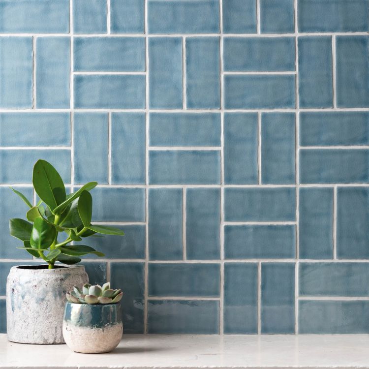 Blaue Fliesenwand im Muster-Mix mit zwei Blumentöpfen